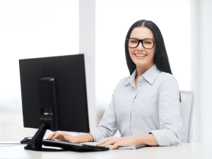 A women sitting at a desk smiling performing customer service.